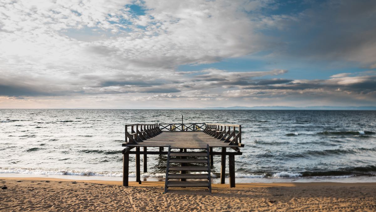 The intersection of a long walk and a short pier on a beach